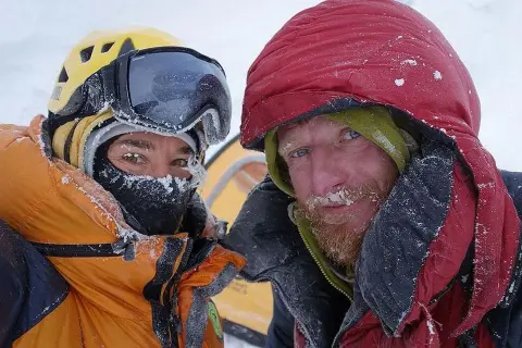 Tomasz Mackiewicz und ein Bergsteigerkollege, bedeckt mit Schnee, blicken in die Kamera.