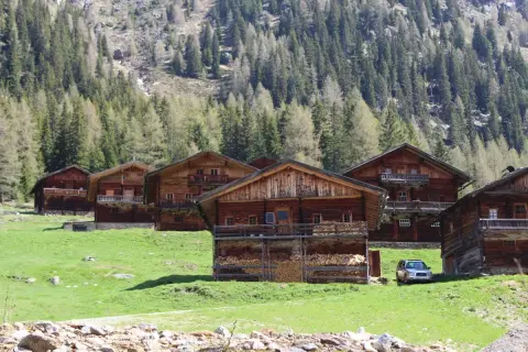 Holzhäuser im Villgratental, umgeben von grünen Wiesen und Nadelwäldern. Eine Karte des Villgratentals würde diese idyllische Landschaft zeigen.