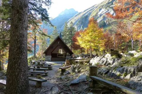 Holzhütte mit Bänken und bunten Bäumen im Herbst. Perfekt für eine Seealpsee Wanderung.