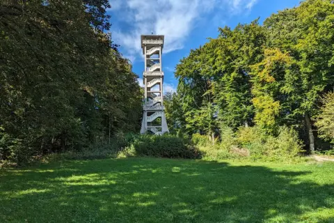 Der Aussichtsturm Ebersberg ragt zwischen grünen Bäumen empor. Eine Außentreppe schlängelt sich nach oben, um eine tolle Aussicht zu ermöglichen.
