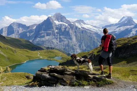 Wanderer mit Hund genießen atemberaubende Aussicht auf Bergseen und Gipfel. Perfekt für mehrtagestouren alpen.