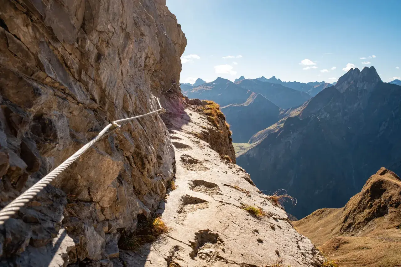 Klettersteig am Laufbacher Eck mit Seilsicherung und Blick auf schroffe Bergketten.