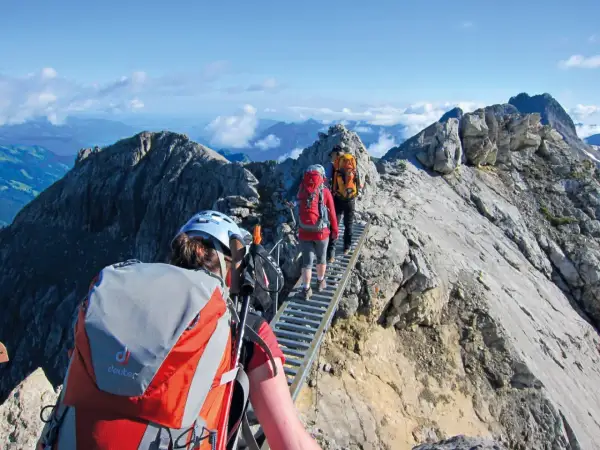 Drei Wanderer auf einer Hängebrücke während einer 5-tägigen Alpenwanderung. Die Aussicht ist atemberaubend.